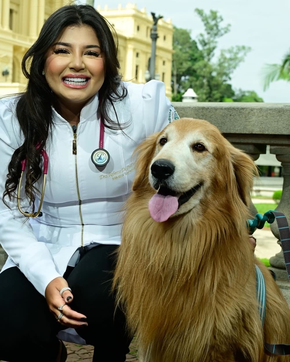 Dra. Rebecca de jaleco branco e estetoscópio, sentada ao lado do Thor, um golden retriever